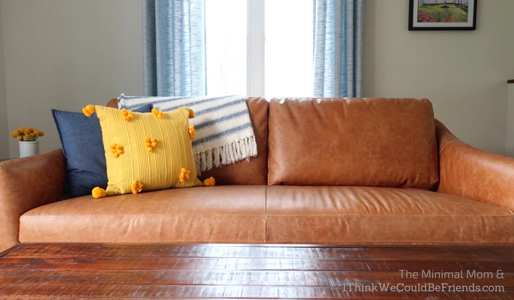 minimalist living room, brown couch, blue and yellow throw pillows